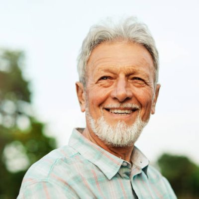 Portrait of an elderly man outdoors. Happy senior man in park